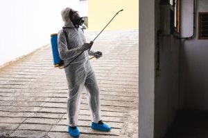 Pest control technician wearing protective gear while performing indoor pest treatment in a commercial building